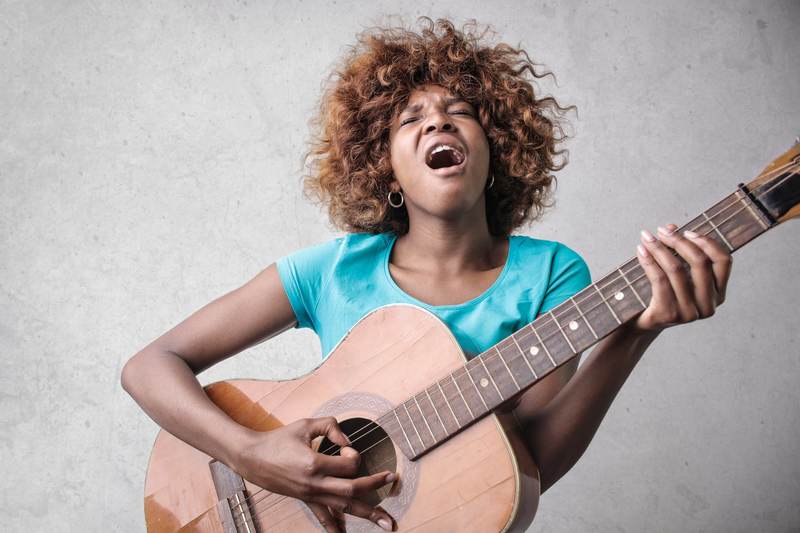 Mulher cantando com um violão