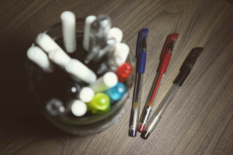 Diversas canetas em um guardador de canetas sobre a mesa.